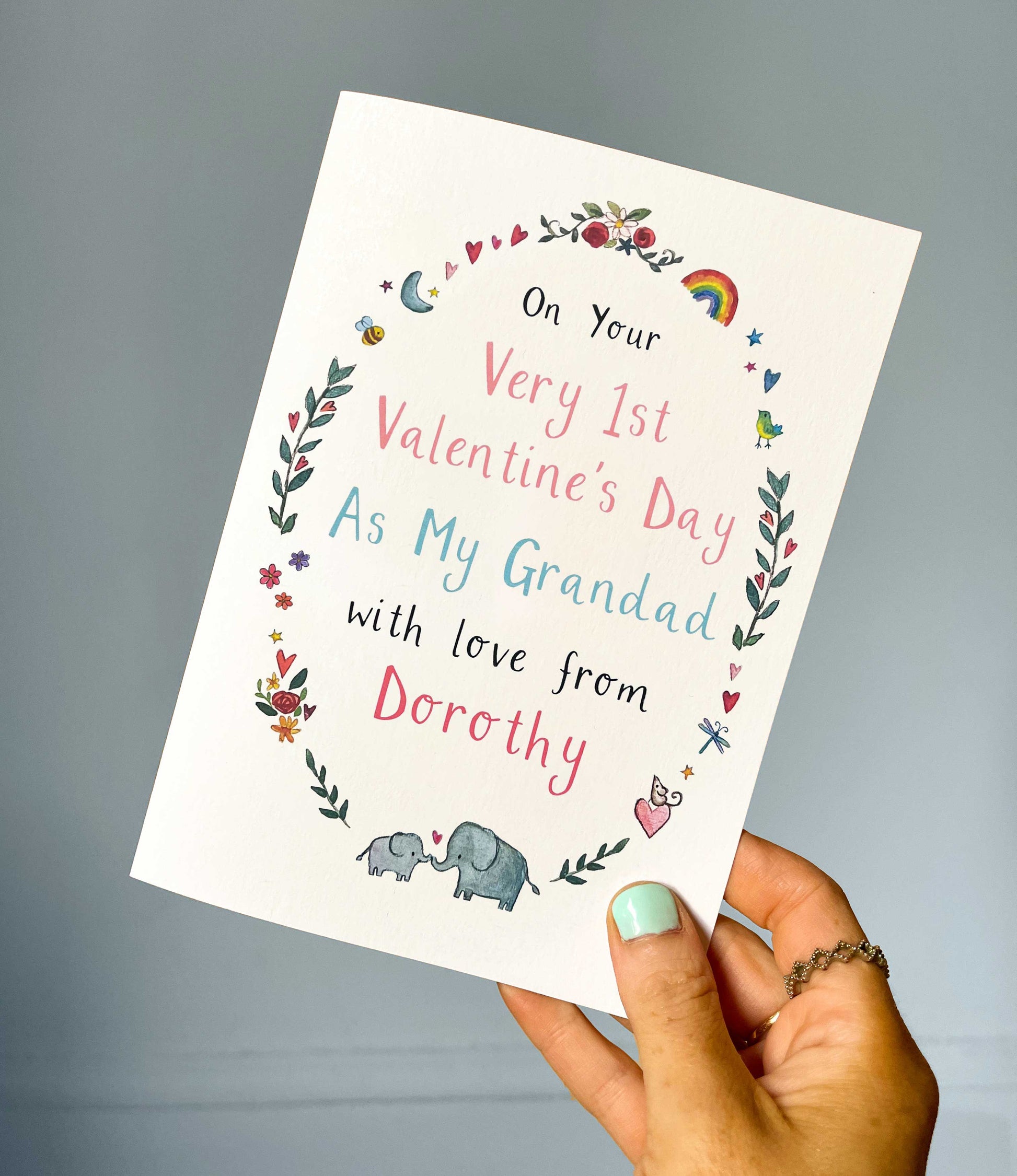 Hand holding a Valentine's Day card for a grandad with decorative text and illustrations.