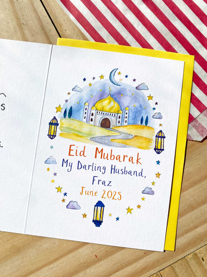 Eid Mubarak card with a mosque illustration on a wooden surface
