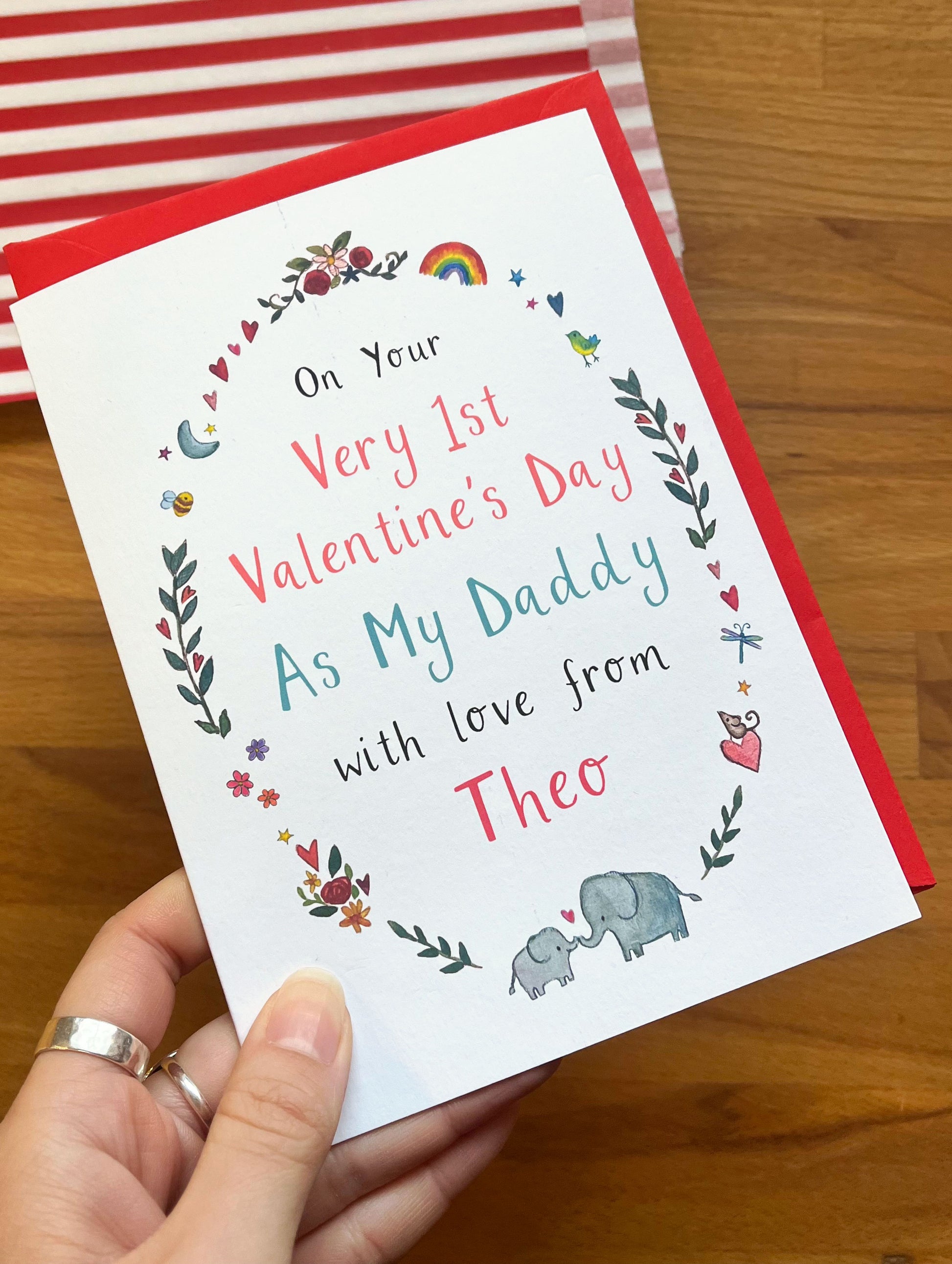 Valentine's Day card for a first Valentine's Day as a father, held by a hand on a wooden surface.