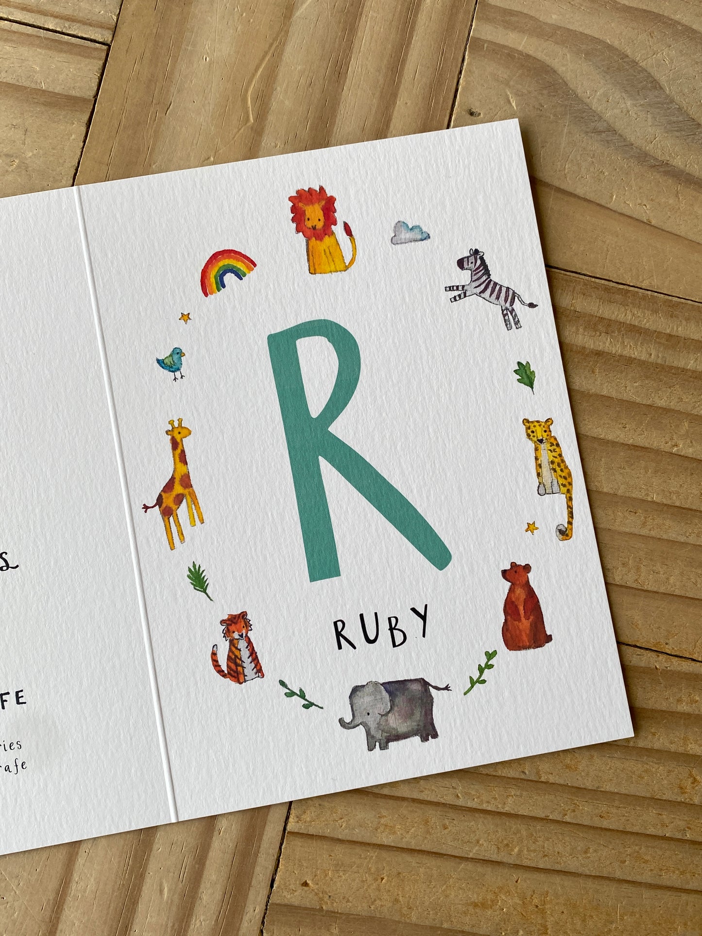 Children's name card with colorful illustrations on a wooden surface