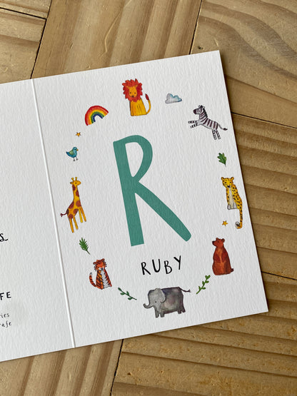 Children's name card with colorful illustrations on a wooden surface