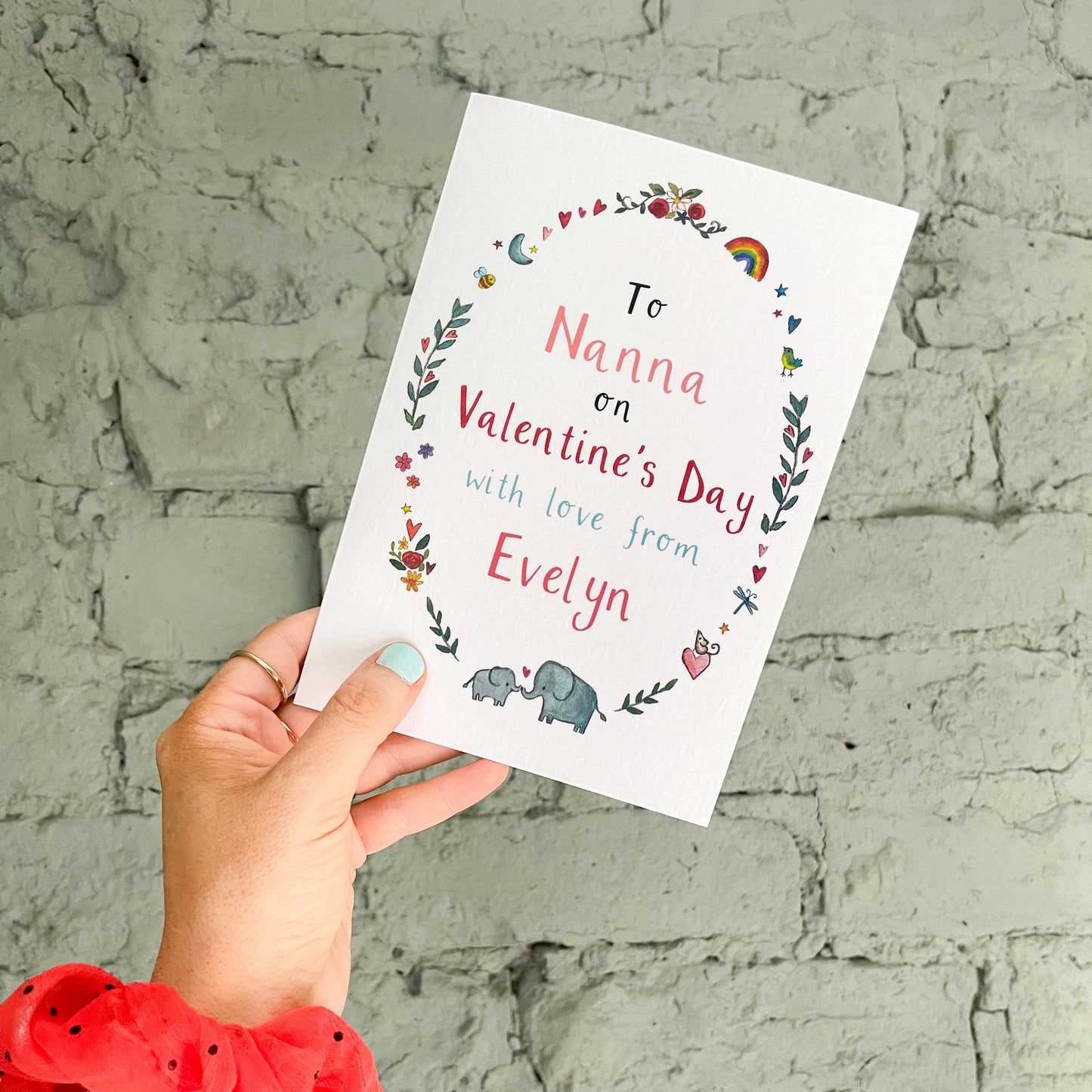 Hand holding a personalised Valentine's Day card for nanna with decorative text against a textured wall.
