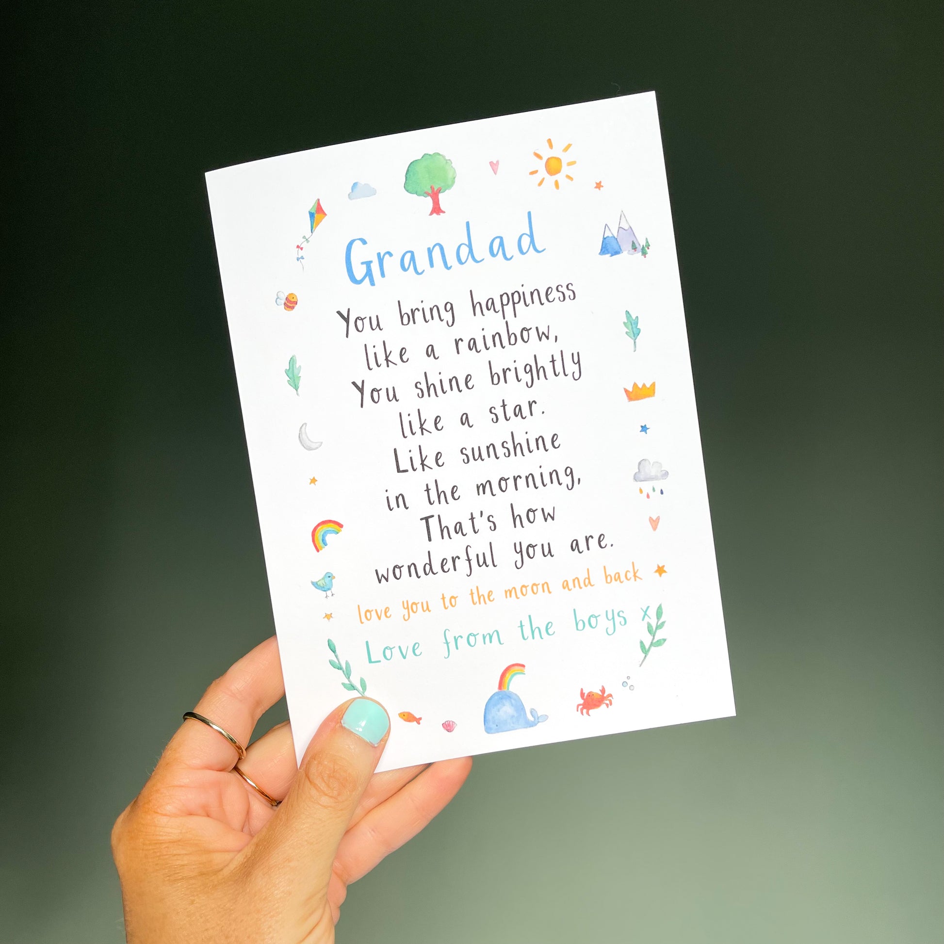 hand holding a white greetings card with the text 'grandad' at the top, a poem underneath and watercolour illustrations surrounding it.