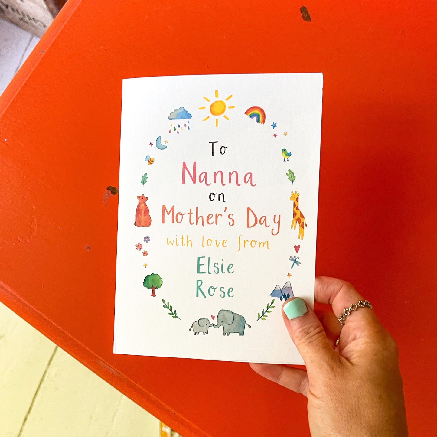 hand holding a greetings card featuring watercolour illustrations and the custom text 'to nanna on mother's day love from Elsie Rose'