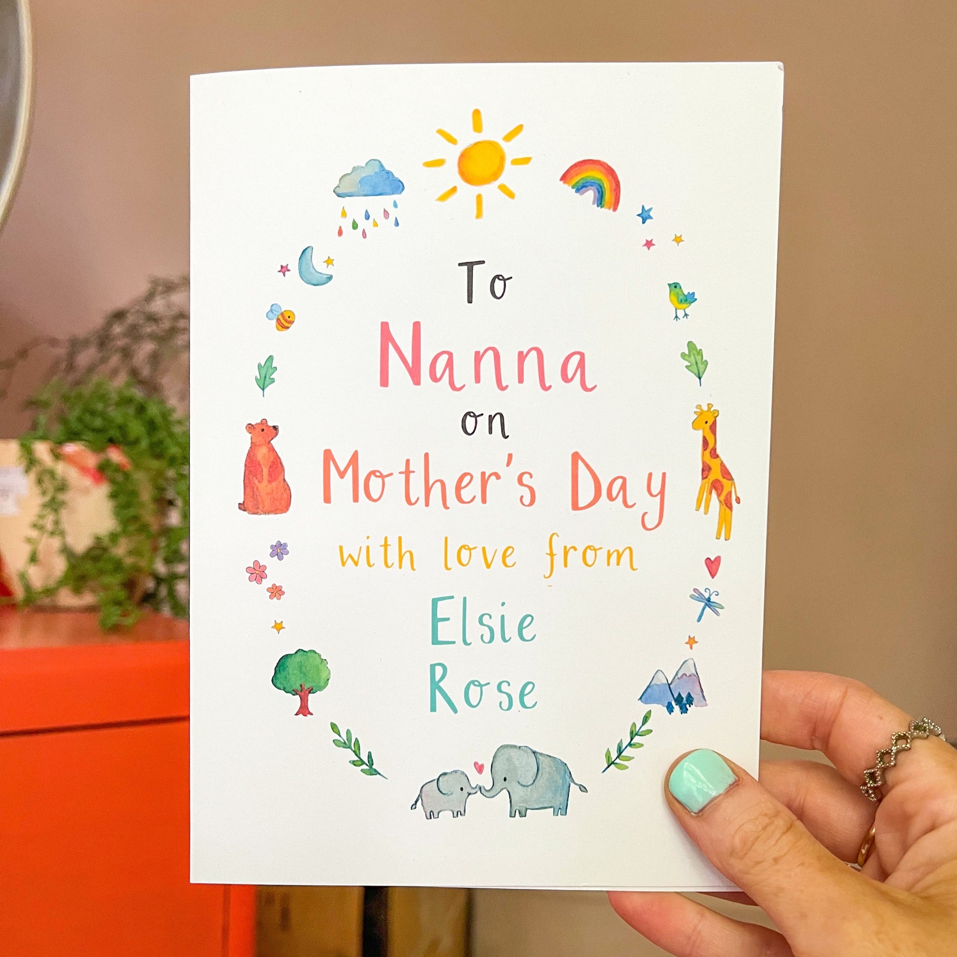 hand holding a greetings card featuring watercolour nature illustrations and the personalised text 'to nanna on mother's day love from Elsie Rose'
