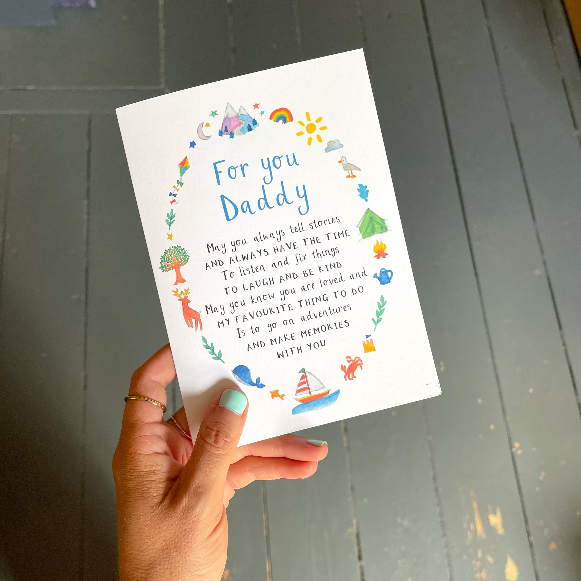 A hand holding a Father's Day card with the text 'for you daddy', a poem and watercolour illustrations