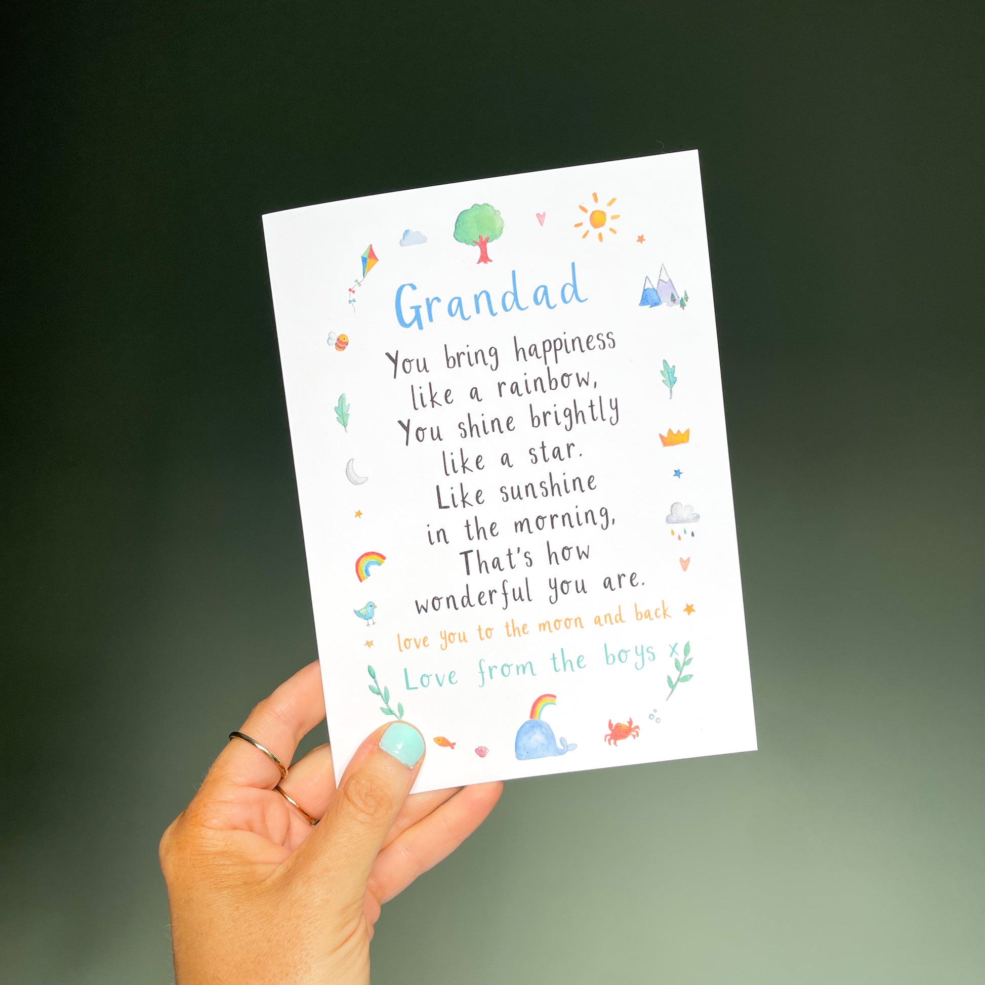 hand holding a white greetings card with the text 'grandad' at the top, a poem underneath and watercolour illustrations surrounding it.
