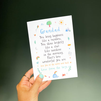 hand holding a white greetings card with the text 'grandad' at the top, a poem underneath and watercolour illustrations surrounding it.