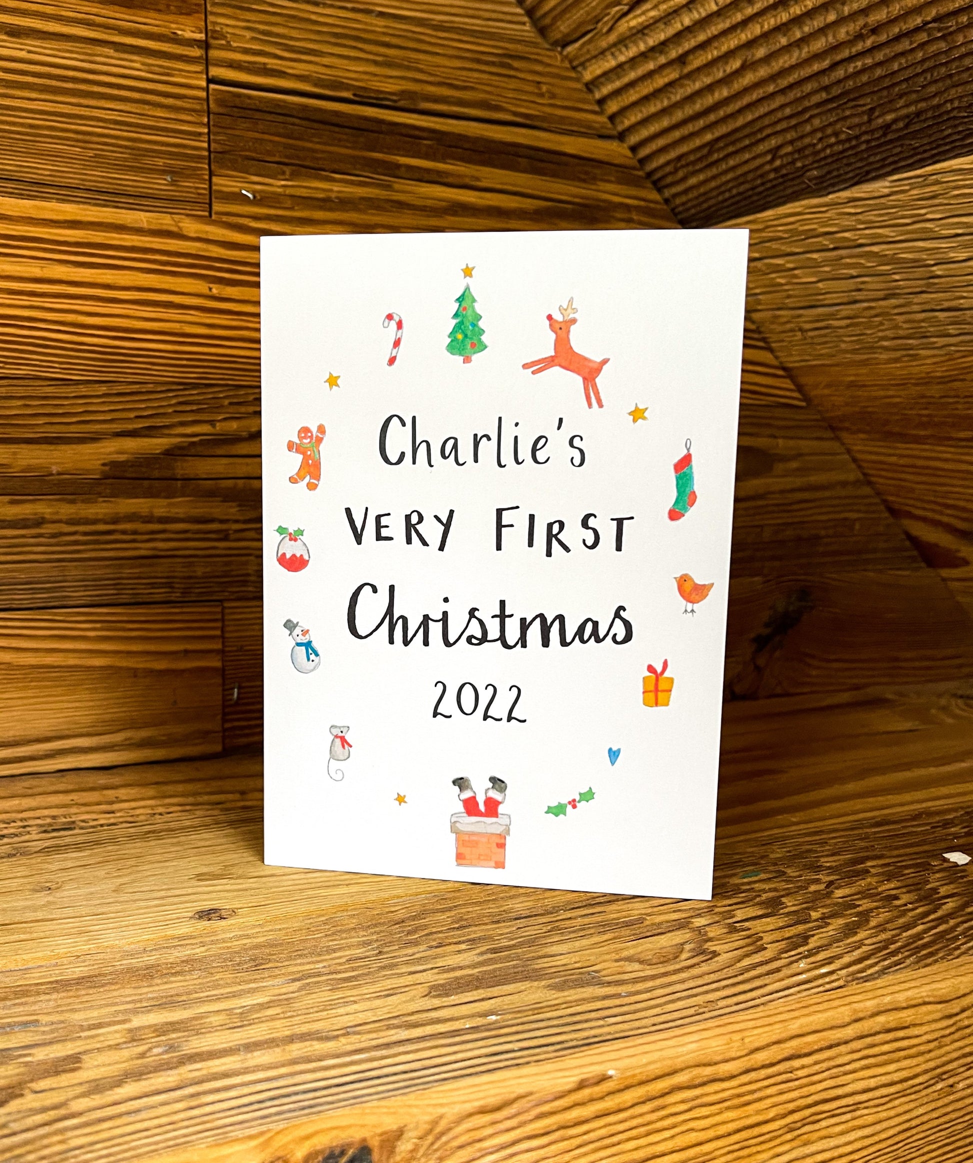 white greetings card with christmas watercolour illustrations and the text 'charlies very first christmas'